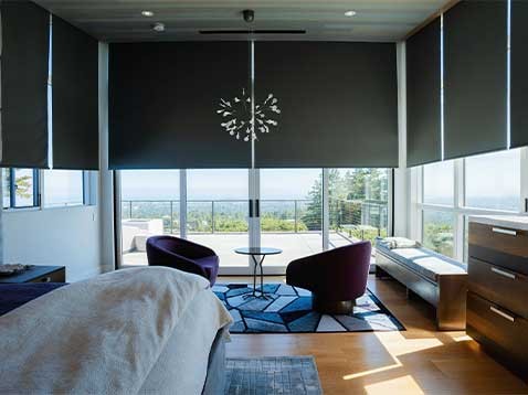 Modern bedroom with large windows covered by black roller-shades