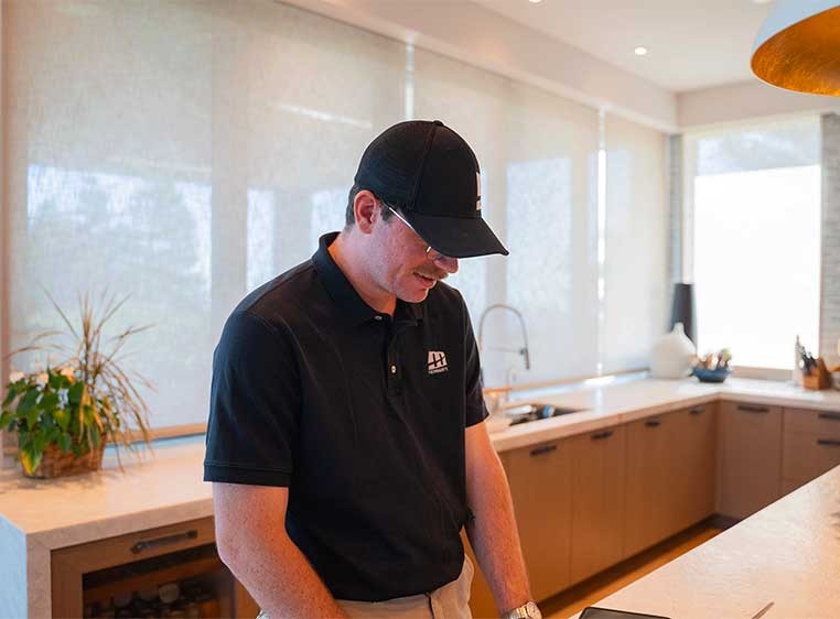 Man wearing a black hat and polo working in a large, modern kitchen